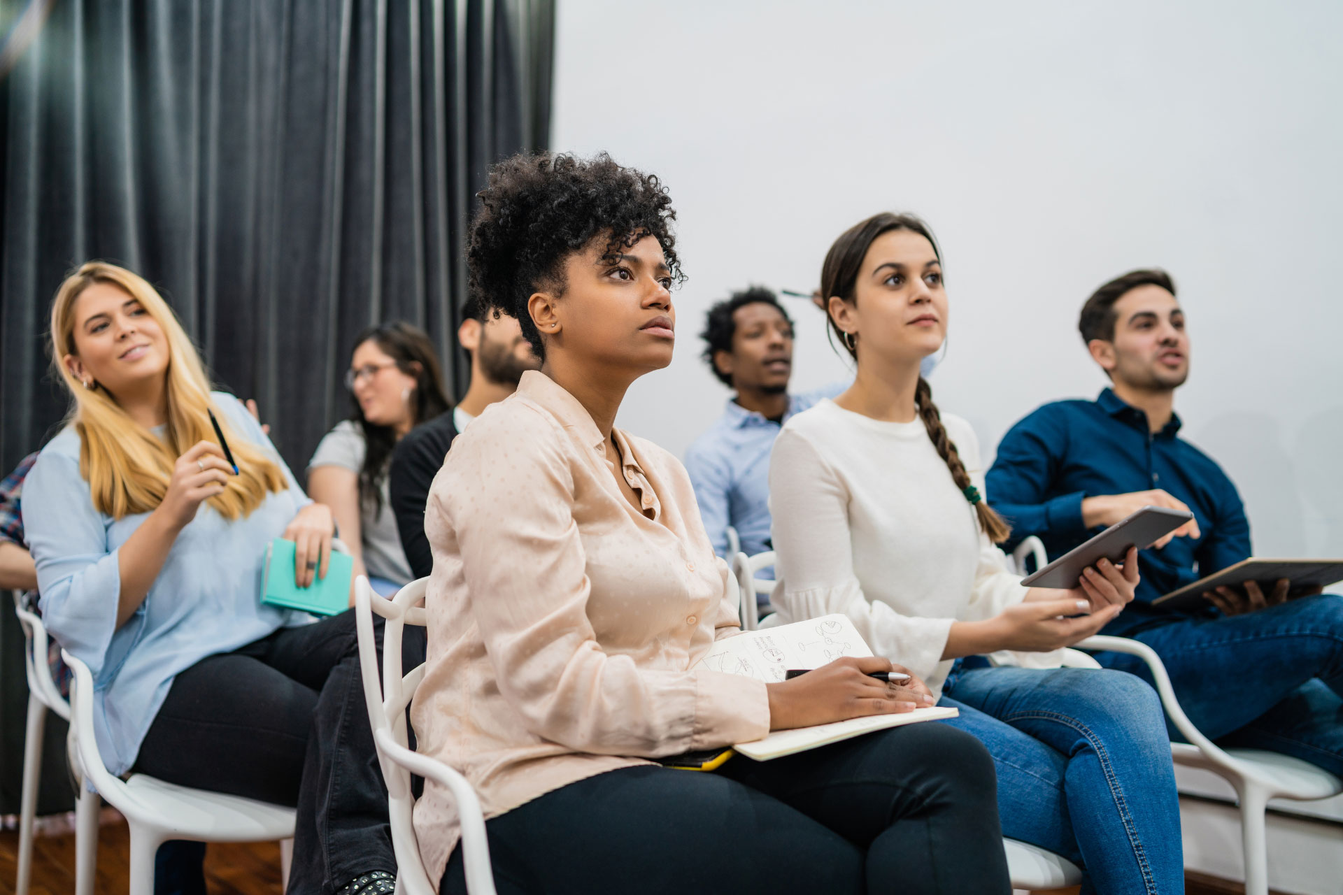 Employees sitting in a room, in rows, taking a corporate English language class