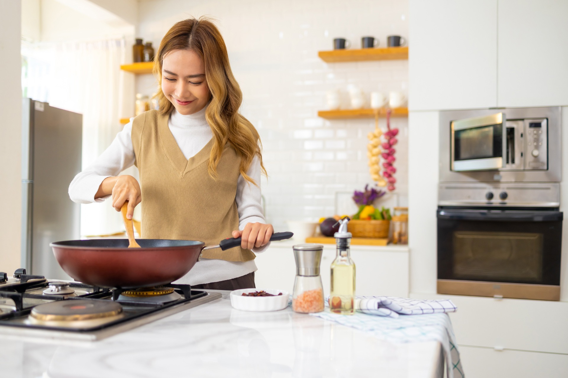 A young woman happily cooking at home