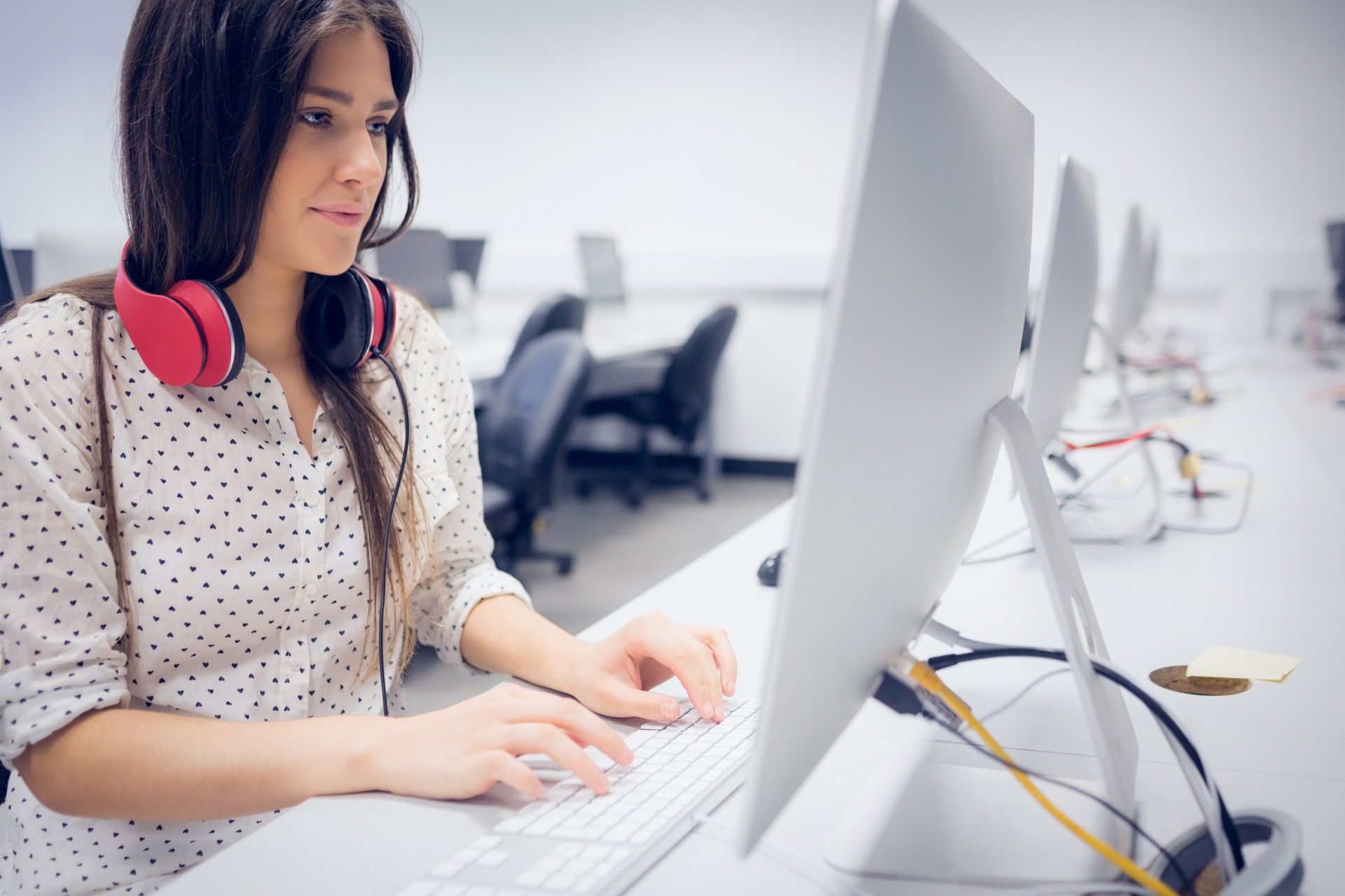 Young woman with red headphones around her neck using a computer