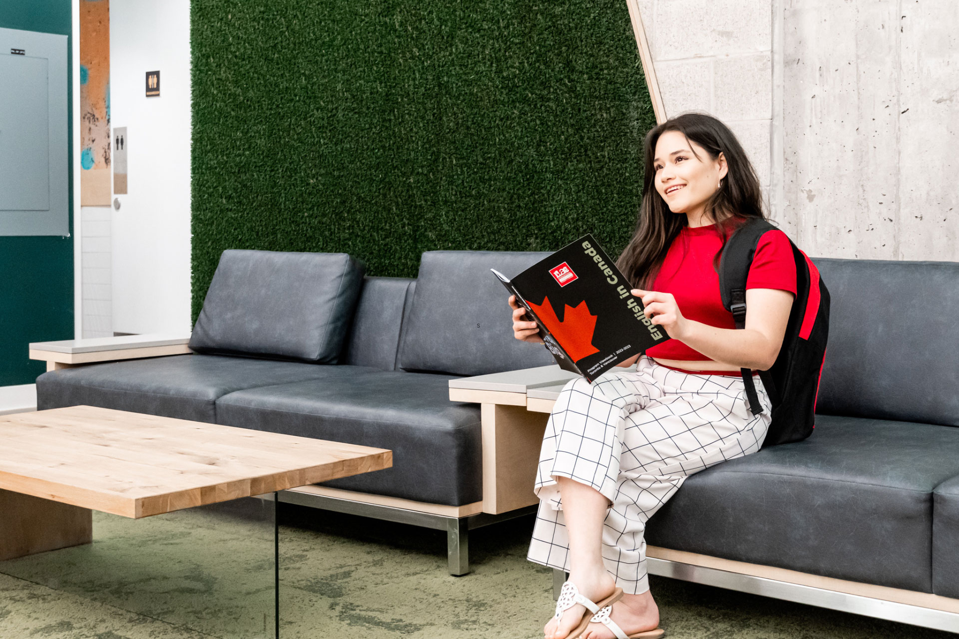 A young woman sitting on a sofa holding ILAC’s program viewbook