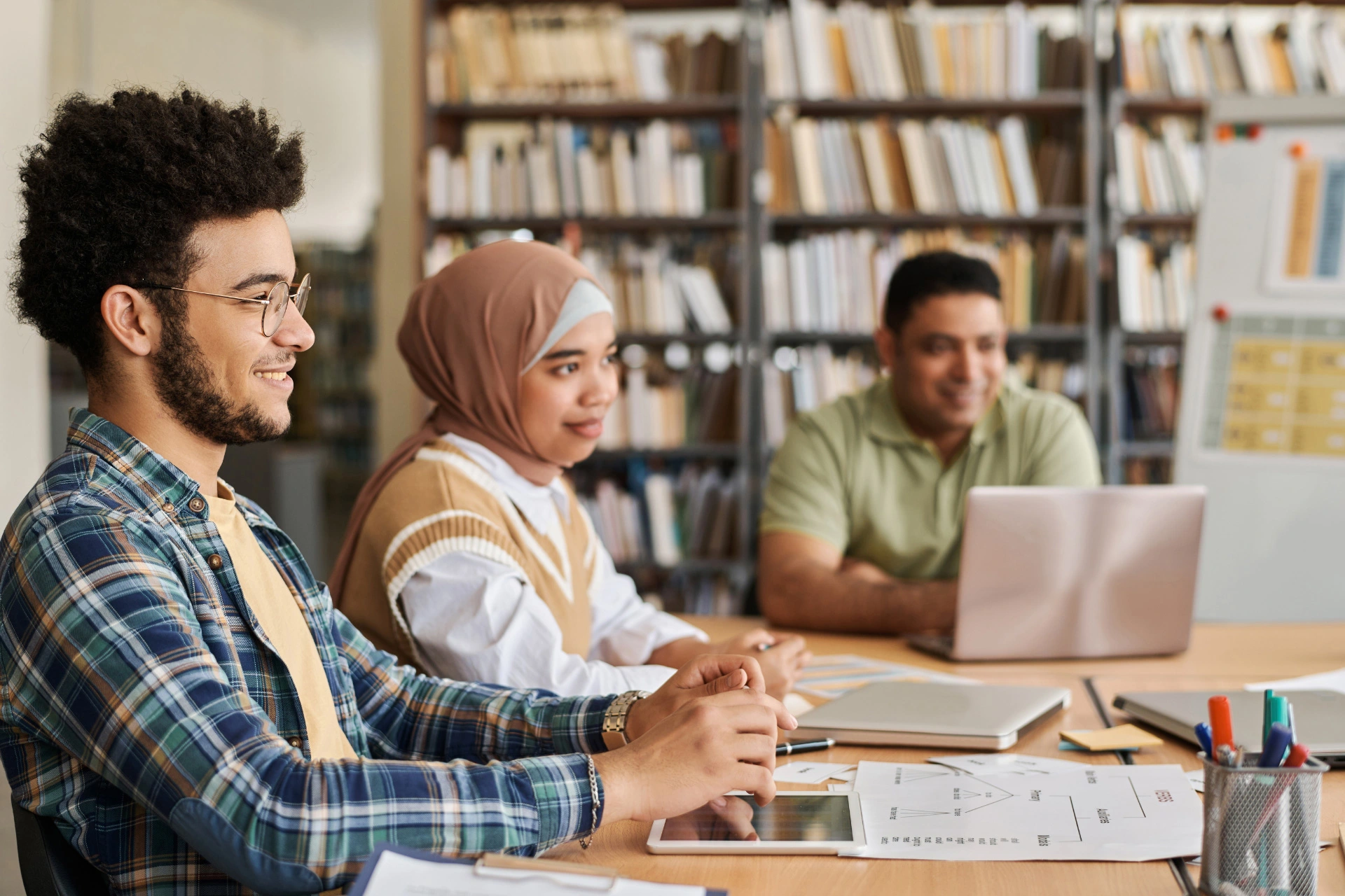 Three students gathered around a table, learning together.