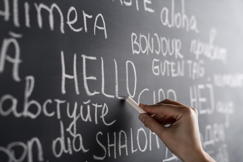 The word "hello" is written on a chalkboard, accompanied by its translations in various languages.